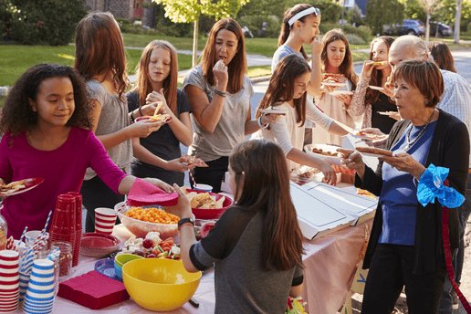 Een lange tafel vol eten waar mensen aan staan