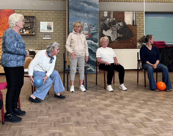 Deelnemers aan stoelyoga gooien met de bal