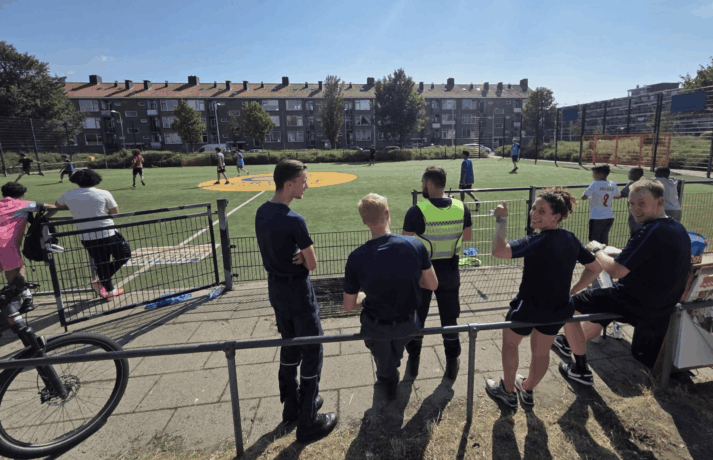 Politie, handhaving, jongerenwerk en toeschouwers langs de lijn van de voetbalwedstrijd