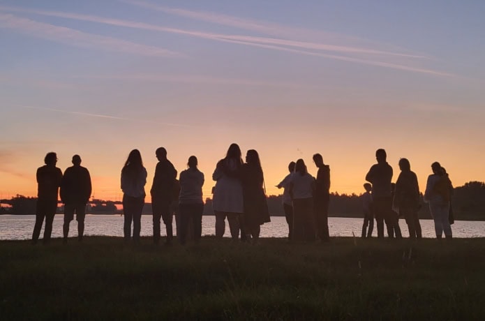 Groep jongeren bij het water tijdens zonsondergang