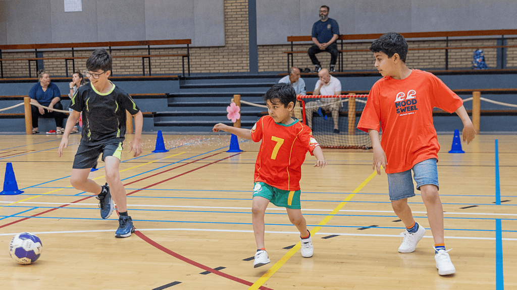 Drie jongens aan het voetballen tijdens het openingsfeest van Zomerpret