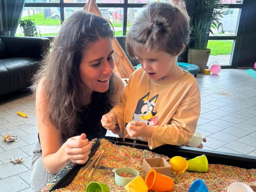 Meisje en haar moeder spelen met sensory rijst